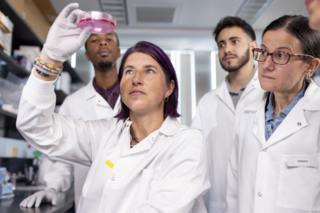 Researchers in white lab coats working together in a lab
